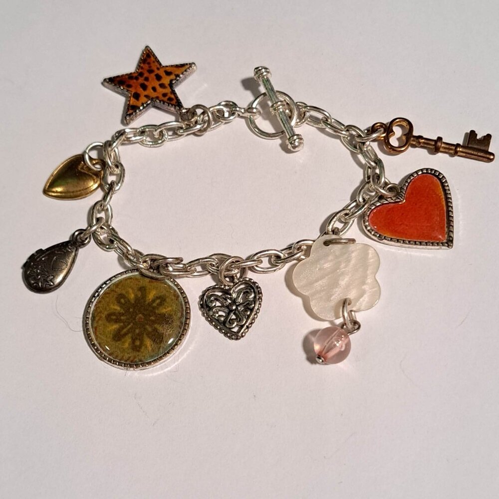 Silver tone charm bracelet with hearts, stars, tear drops, flowers and more